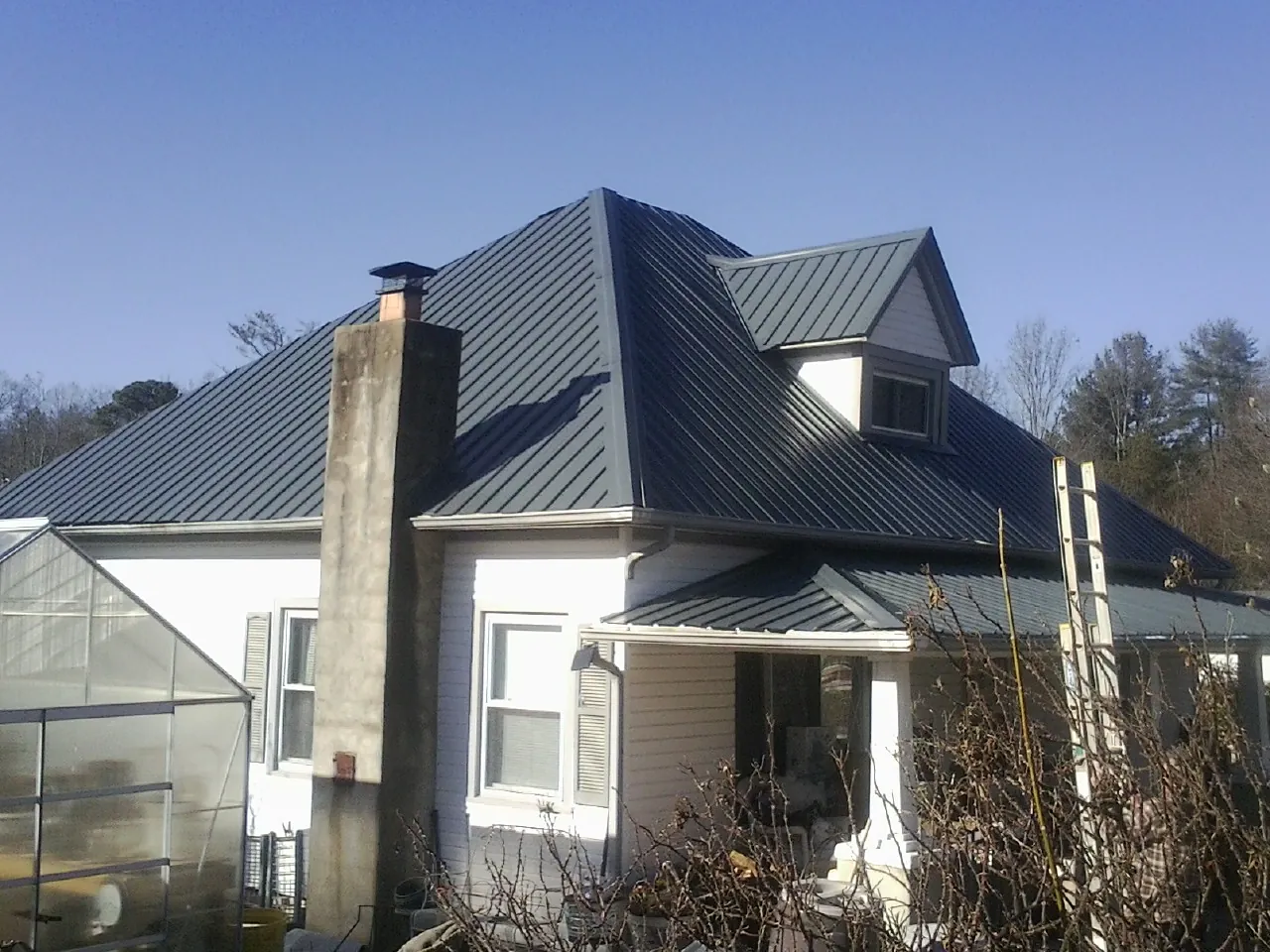 Dark blue standing seam metal roof on a white farmhouse with dormer — Slate & Tile Roof Repair by Roofing Brothers in Twain