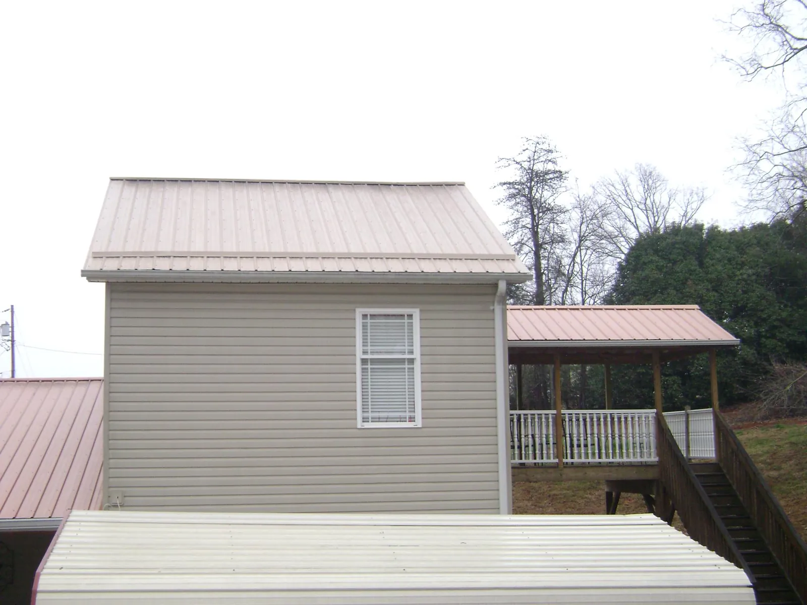 Tan metal roofs on a two story addition and attached porch, from a Roof Replacement job in Twain